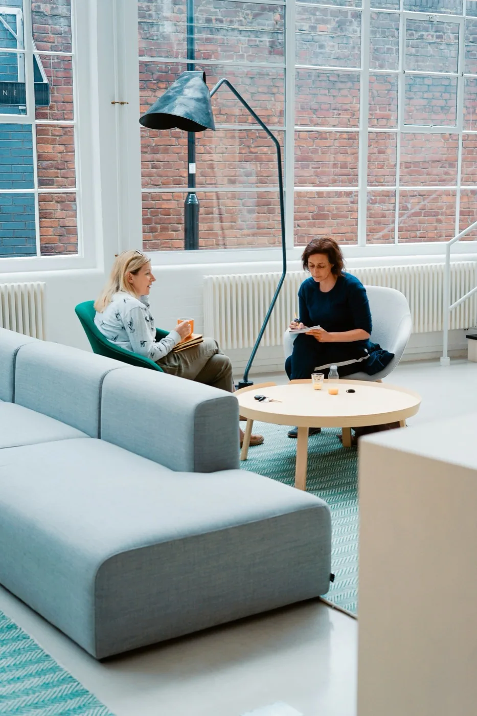 Two colleagues in conversation in a bright consultation lounge